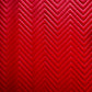 A close-up of a red chevron-patterned quilted fabric with stitched zigzag lines.