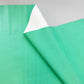 A close-up of a mint green textured sheet, likely vinyl or adhesive film, with a folded corner revealing a white backing, set against a neutral light gray background.