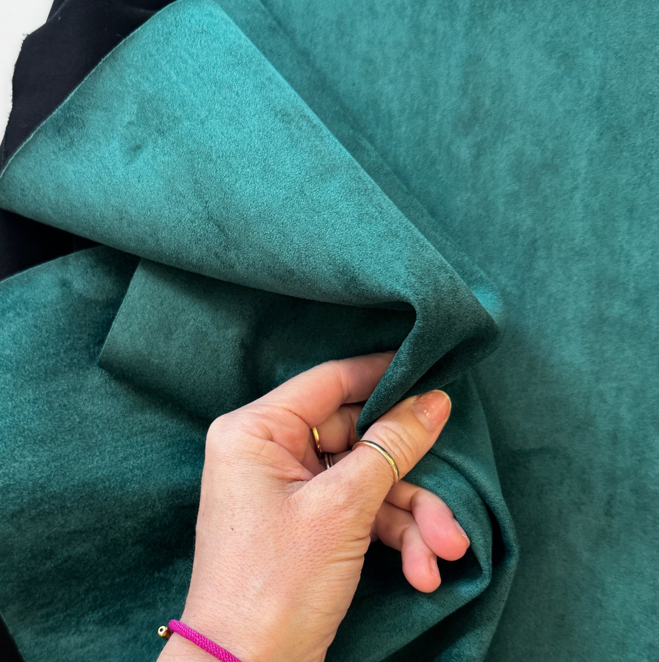 Hand holding teal fabric with a close-up view