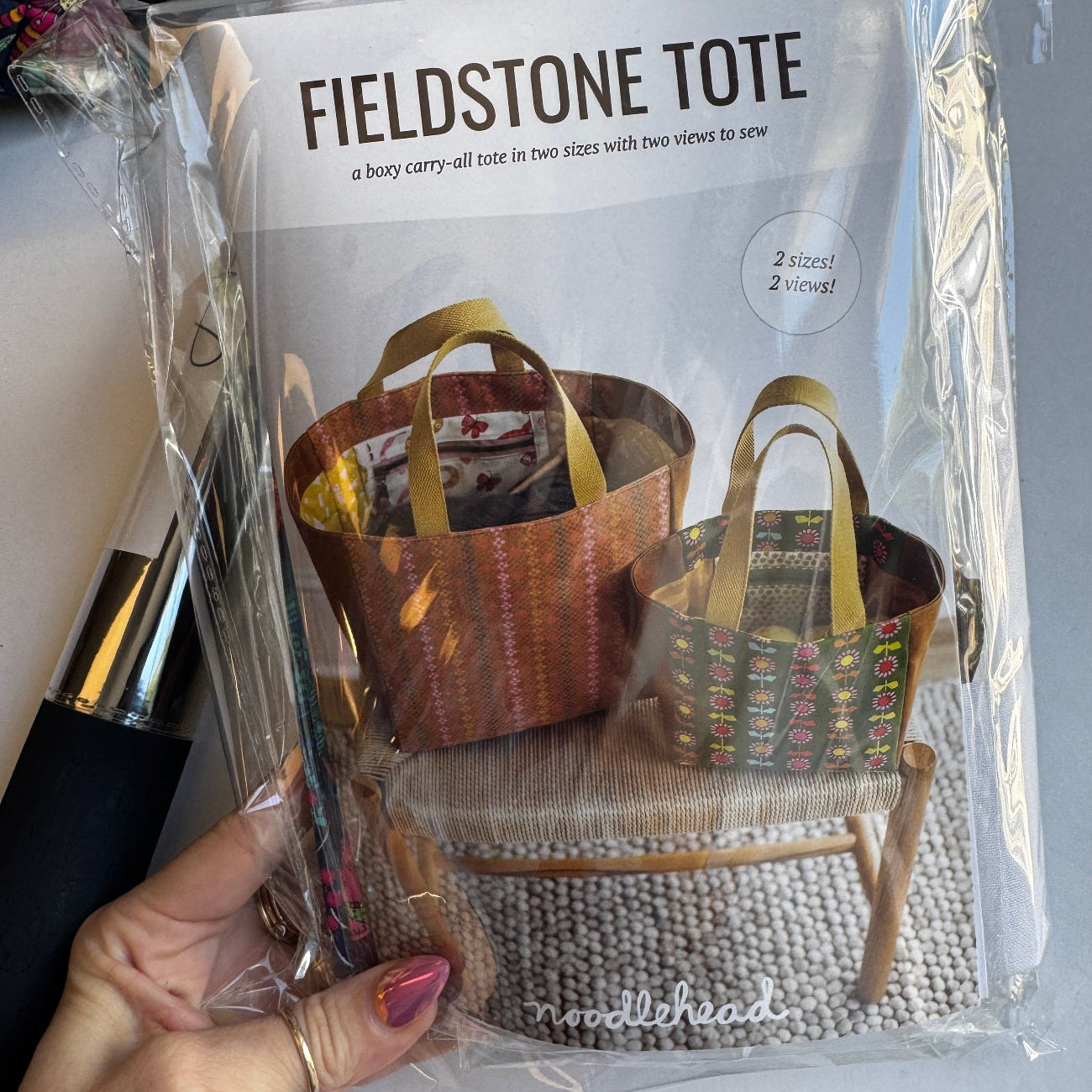 Packaged Fieldstone Tote with a hand holding it against a neutral background
