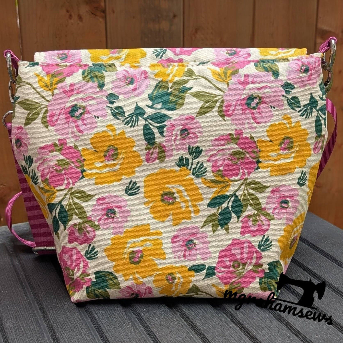 Cream canvas messenger bag with vibrant pink and yellow floral print and green leaves