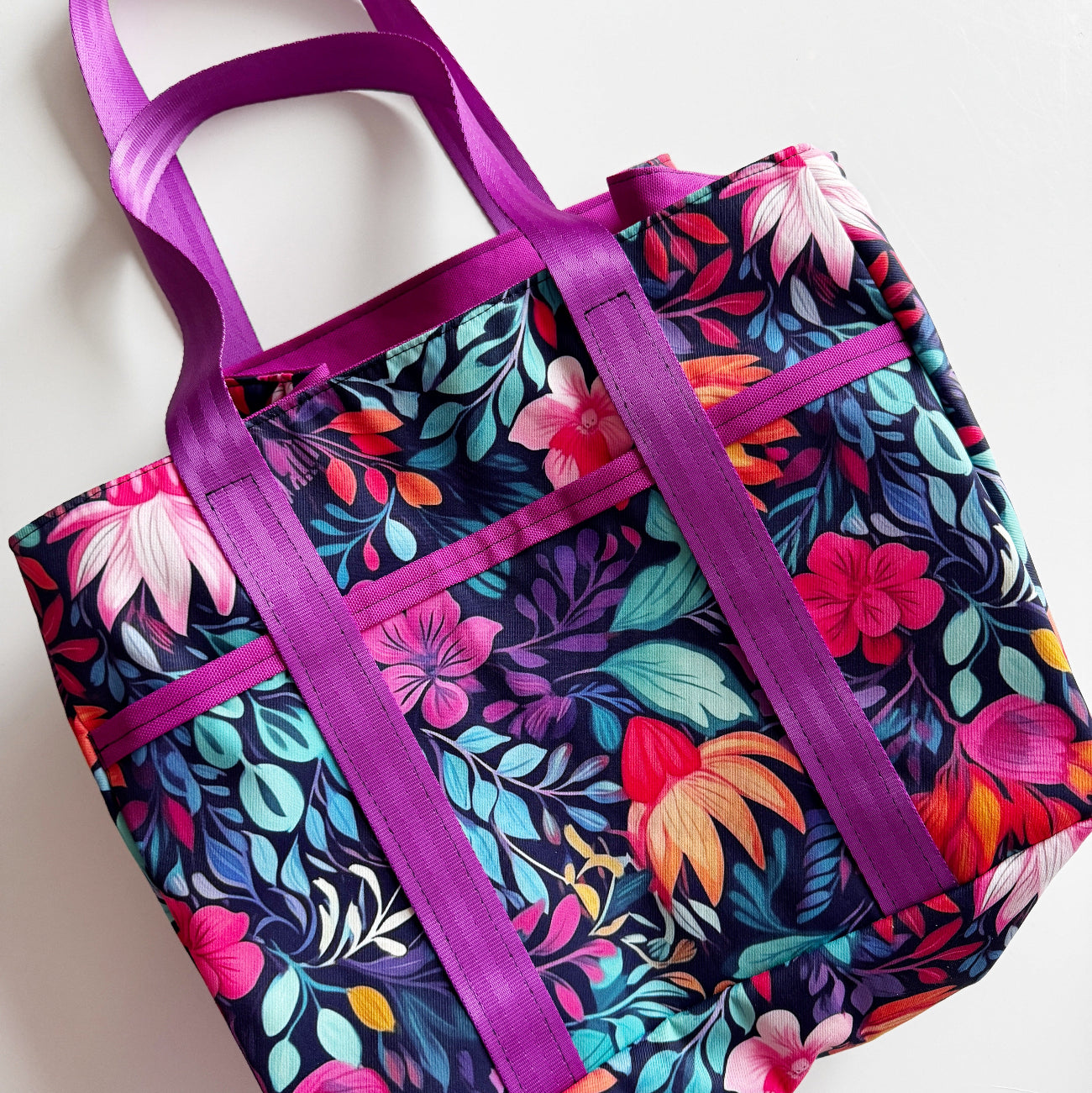 Colorful floral-patterned bag with purple straps on a light background