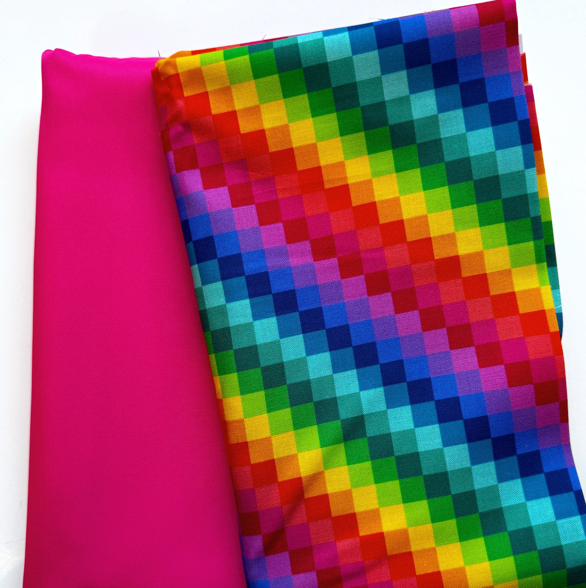 Fuchsia-pink fabric paired with multicolor geometric digital-print fabric in a vibrant pixelated rainbow pattern for bag making