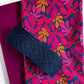 Navy blue clutch with ruffled edge on a pink and blue floral fabric background
