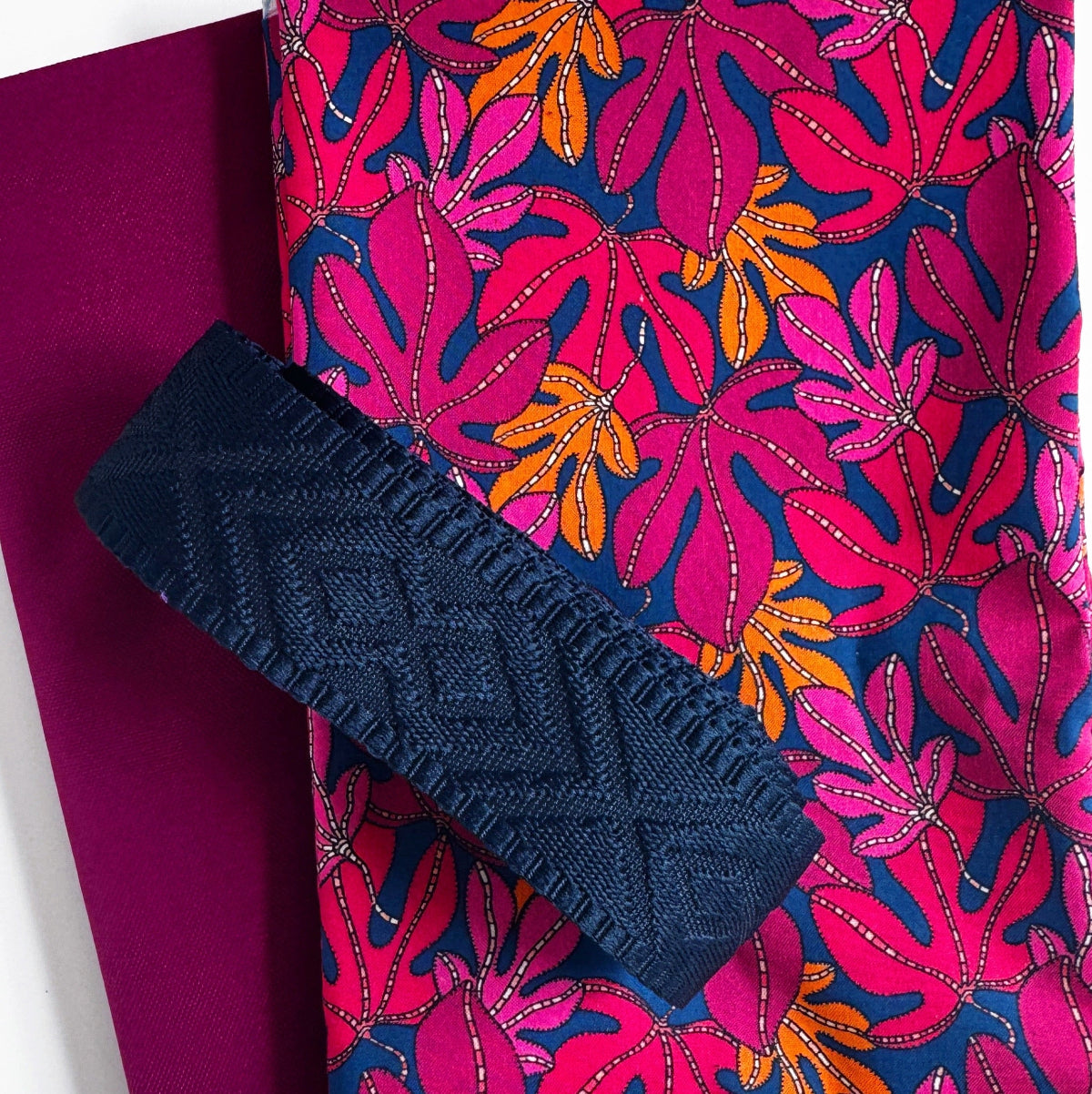 Navy blue clutch with ruffled edge on a pink and blue floral fabric background