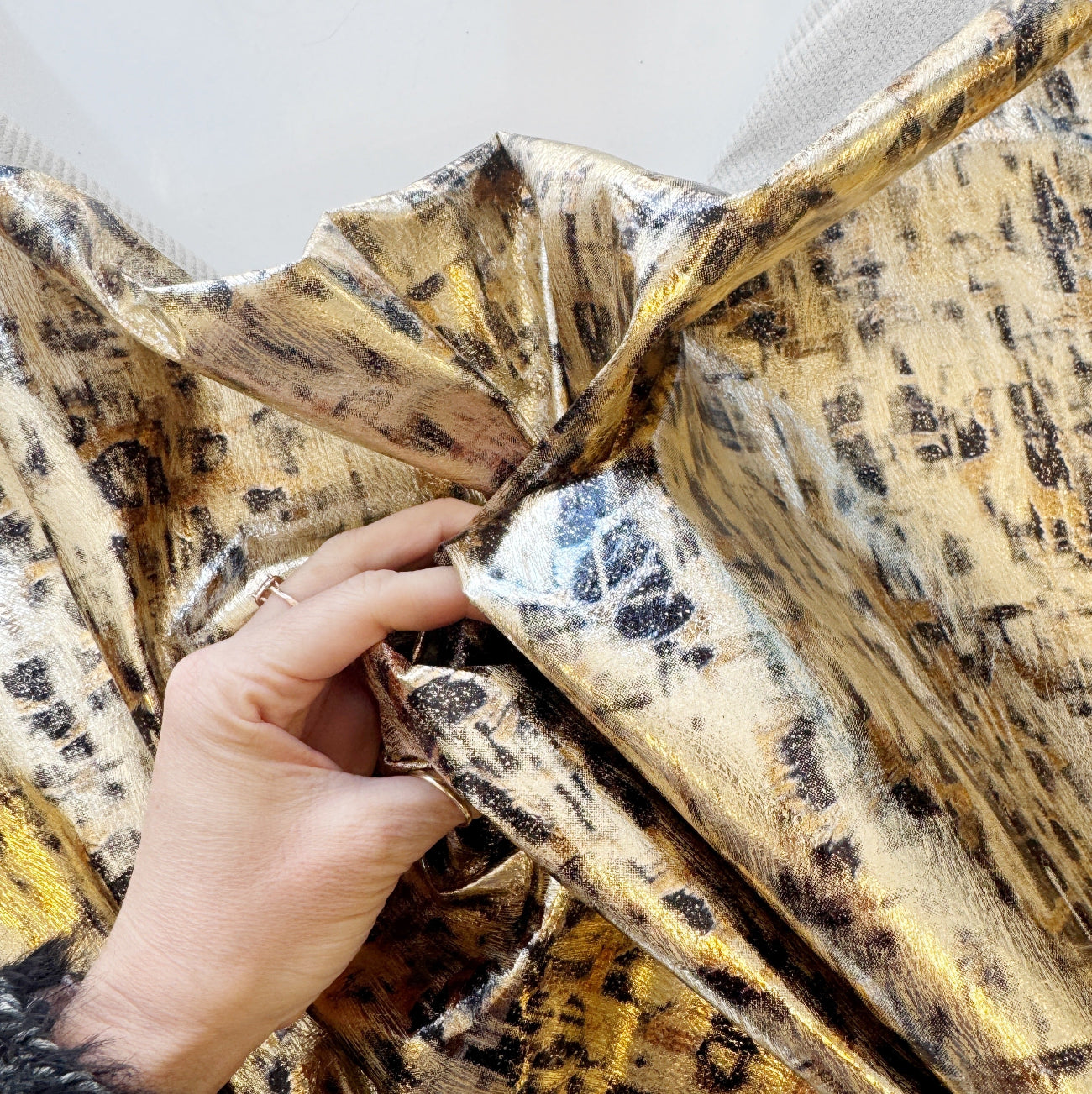 Close-up view of gold and black abstract textured fabric held by hand 
