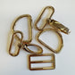 Gold color metal D rings and buckle on a white background