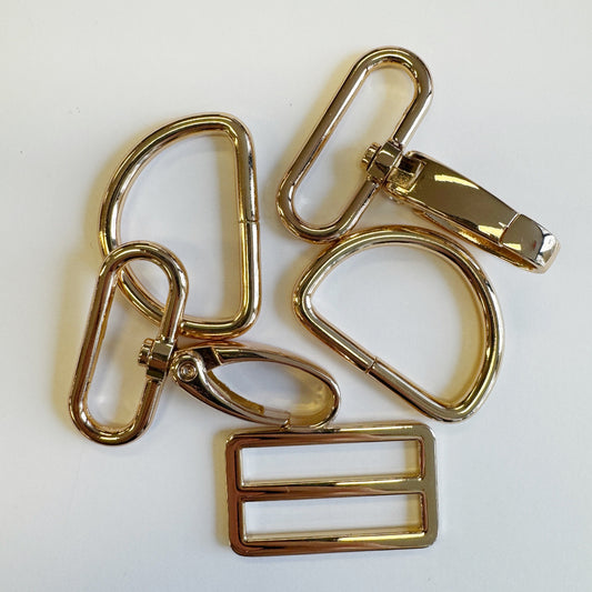 Gold color metal D rings and buckle on a white background