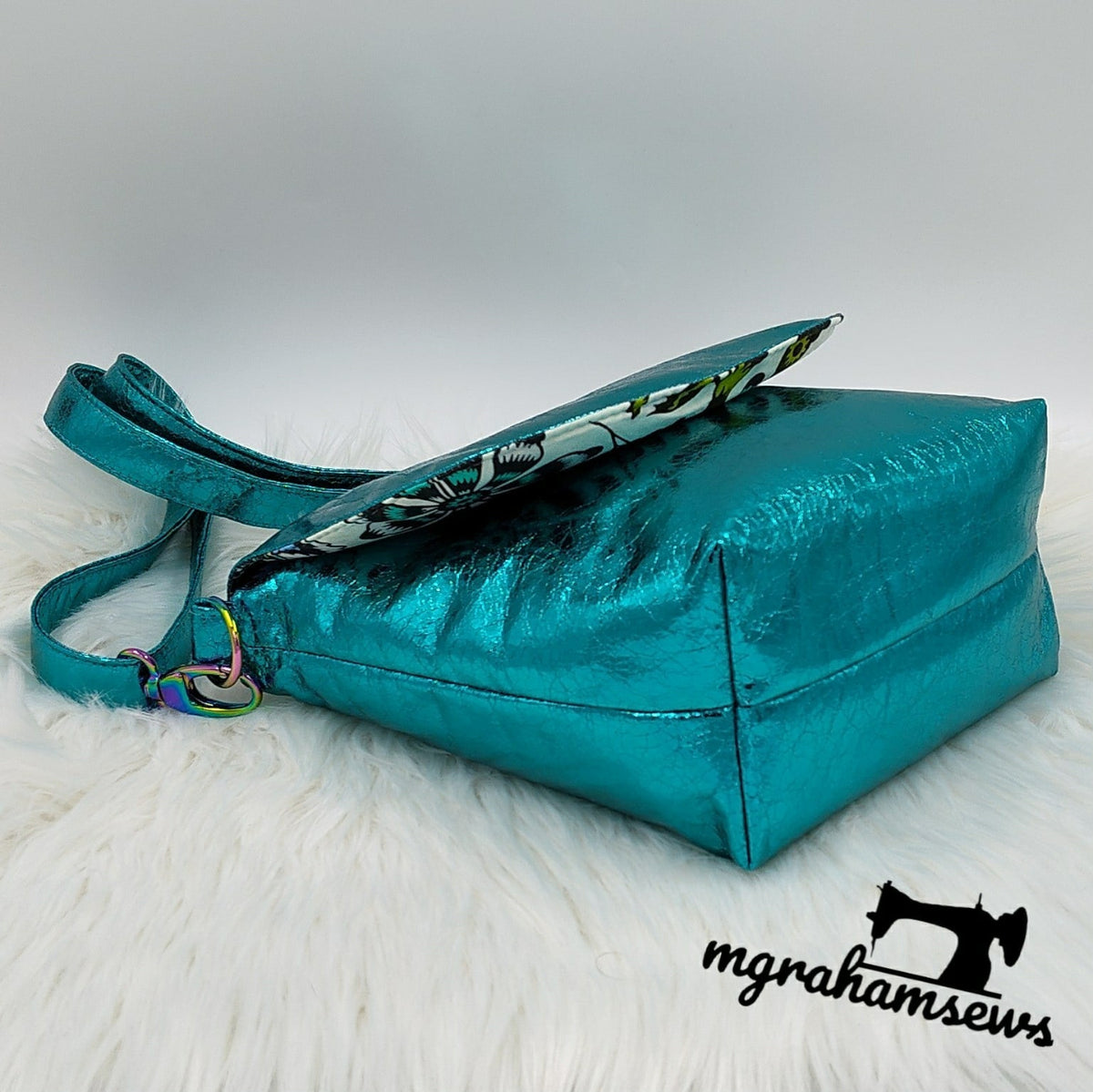 Side view of teal metallic vinyl Iris Messenger Bag showing gusset and adjustable strap