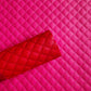Bright pink quilted faux leather material with a rolled corner showing the texture and stitching, set against a matching flat quilted background.