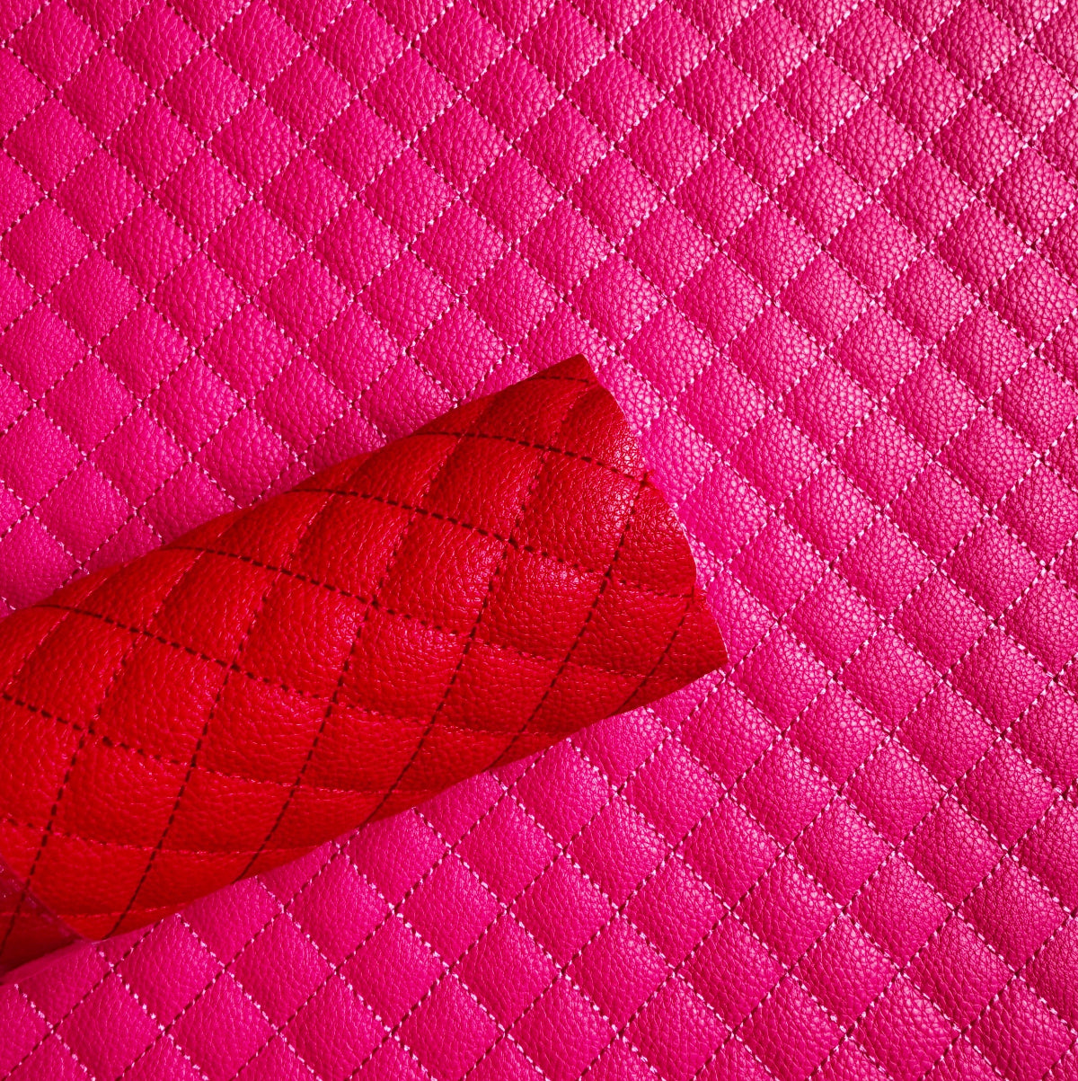Bright pink quilted faux leather material with a rolled corner showing the texture and stitching, set against a matching flat quilted background.