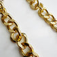 Angled view of two parallel rows of a chunky gold tone acrylic chain showing smooth polished oval links on a white background.