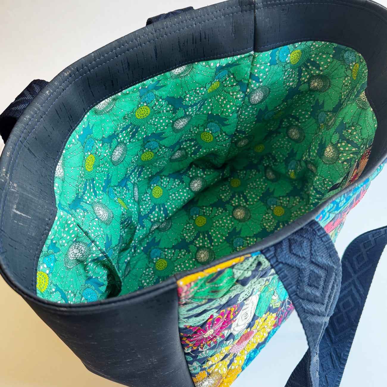 Close-up of a blue bag with a green floral interior lining.