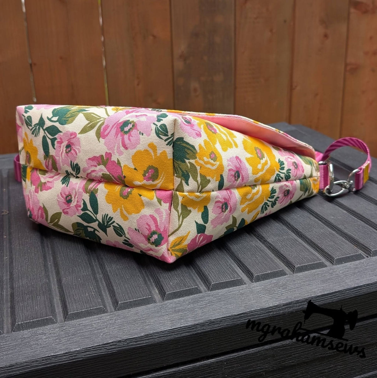 Handmade messenger iris bag in a vibrant pink and yellow floral canvas print paired with an adjustable pink strap.