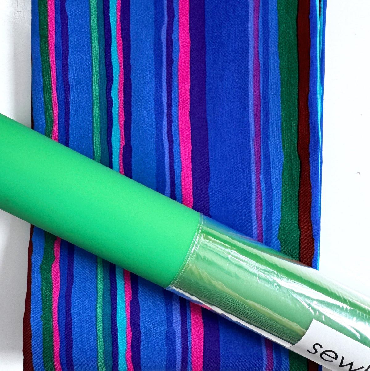 Green fabric roll with colorful striped pattern in the background
