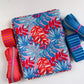 uly Canvas Club bundle featuring a folded pink and blue tropical leaf print canvas fabric surrounded by coordinating striped orange and blue bag webbing and zippers by the yard