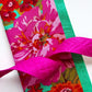 Kaffe Fassett and Tula Pink coordinating fabric bundle for bag making, featuring vibrant pink floral fabric, bright green accent fabric, and a hot pink jacquard woven webbing strap