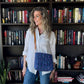 Woman standing in front of a bookshelf with a blue patterned bag