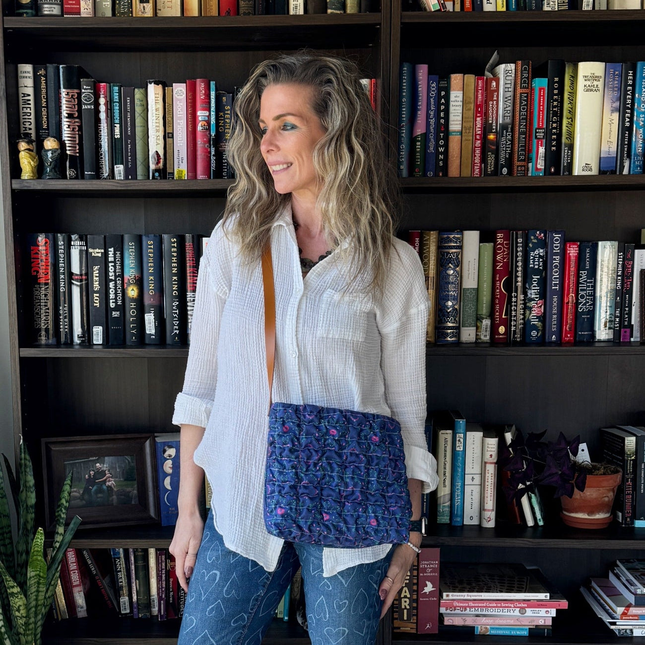Woman standing in front of a bookshelf with a blue patterned bag