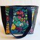 Colorful floral-patterned tote bag with black accents on a white background