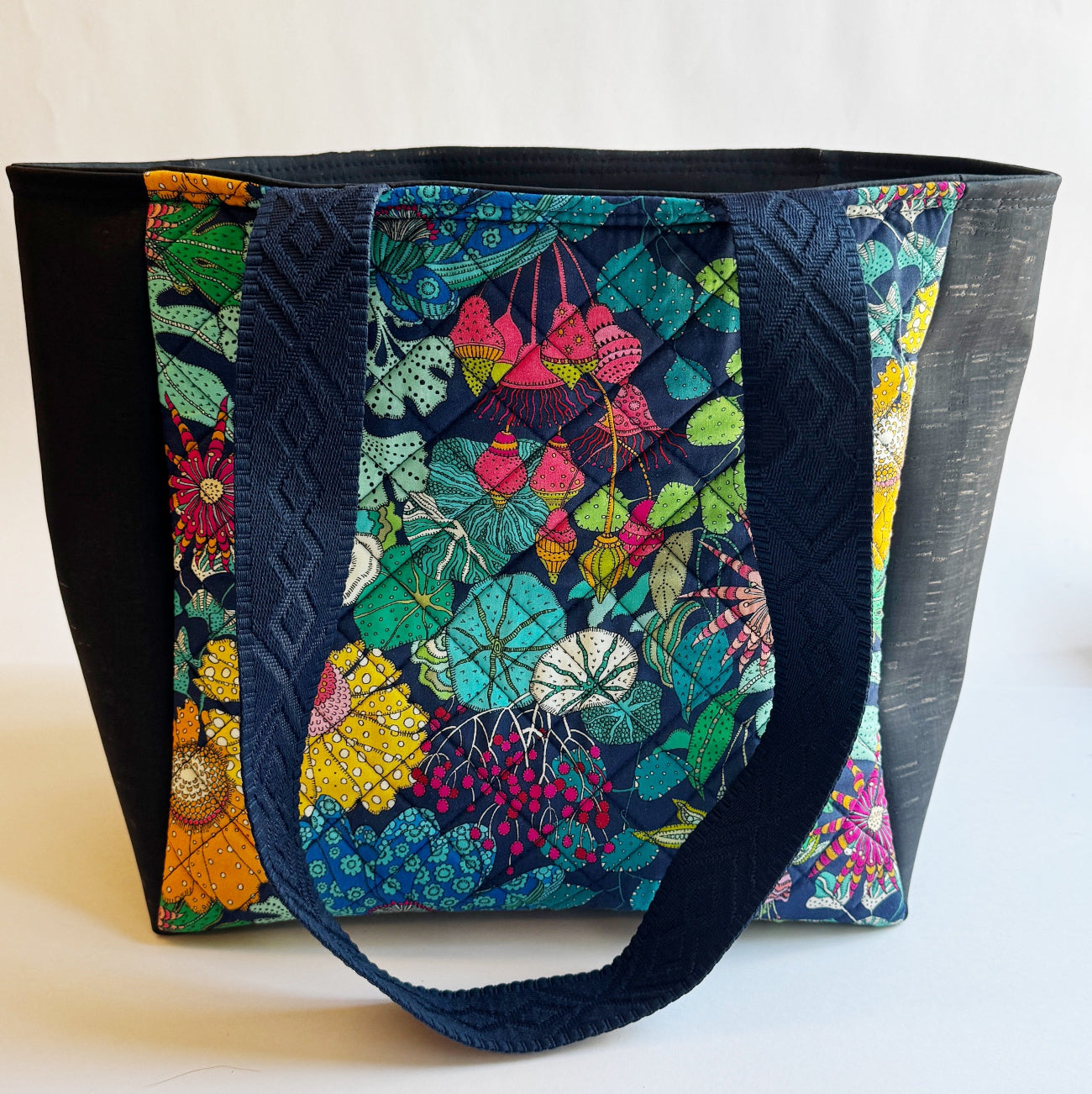 Colorful floral-patterned tote bag with black accents on a white background