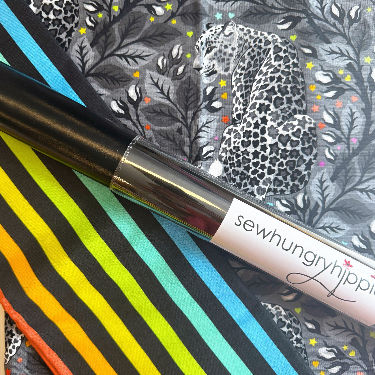 Monochrome leopard print fabric with colorful stars paired with rainbow striped fabric and a roll of black Sew Hungry Hippie vinyl.