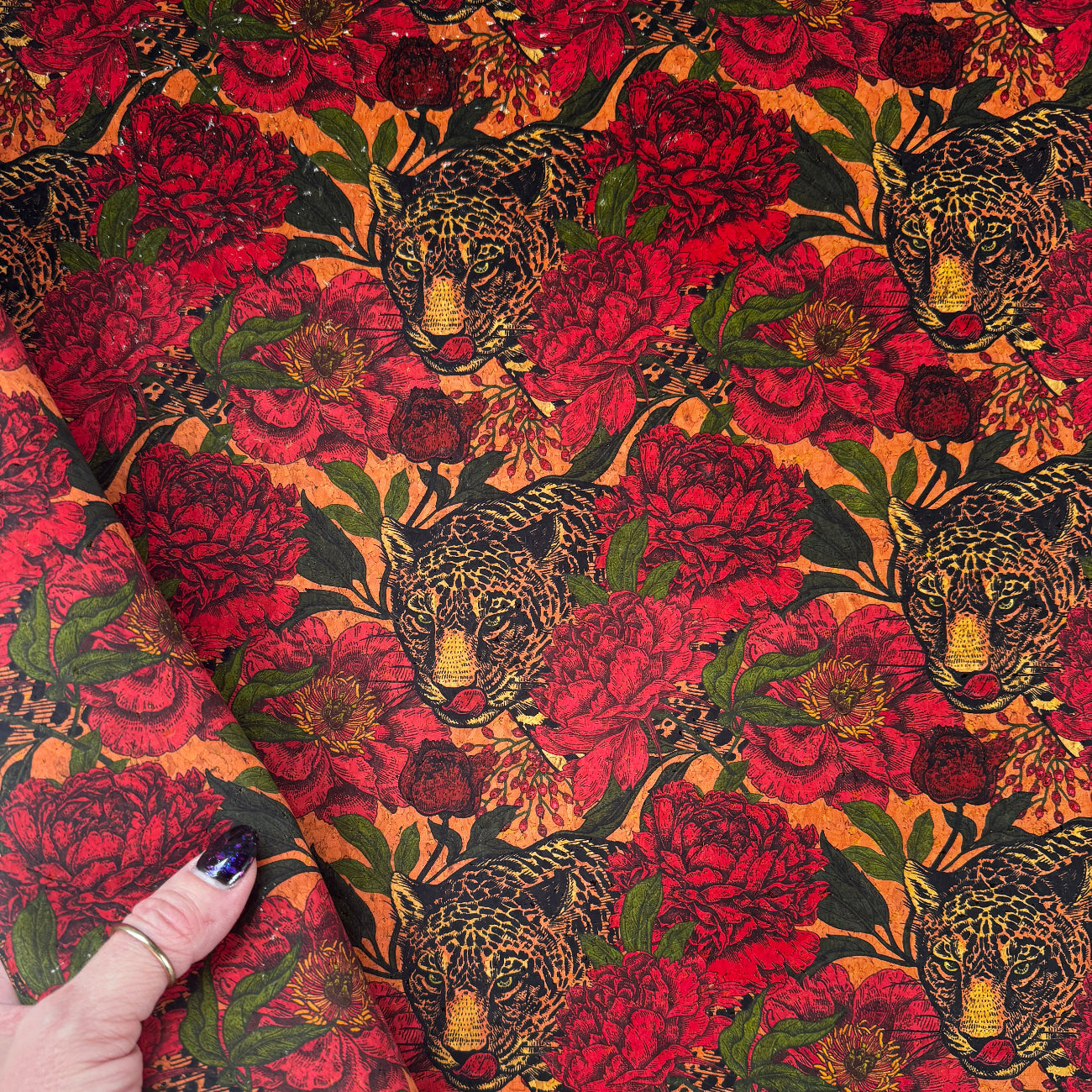 Decorative fabric with intricate patterns held by a hand on a white background