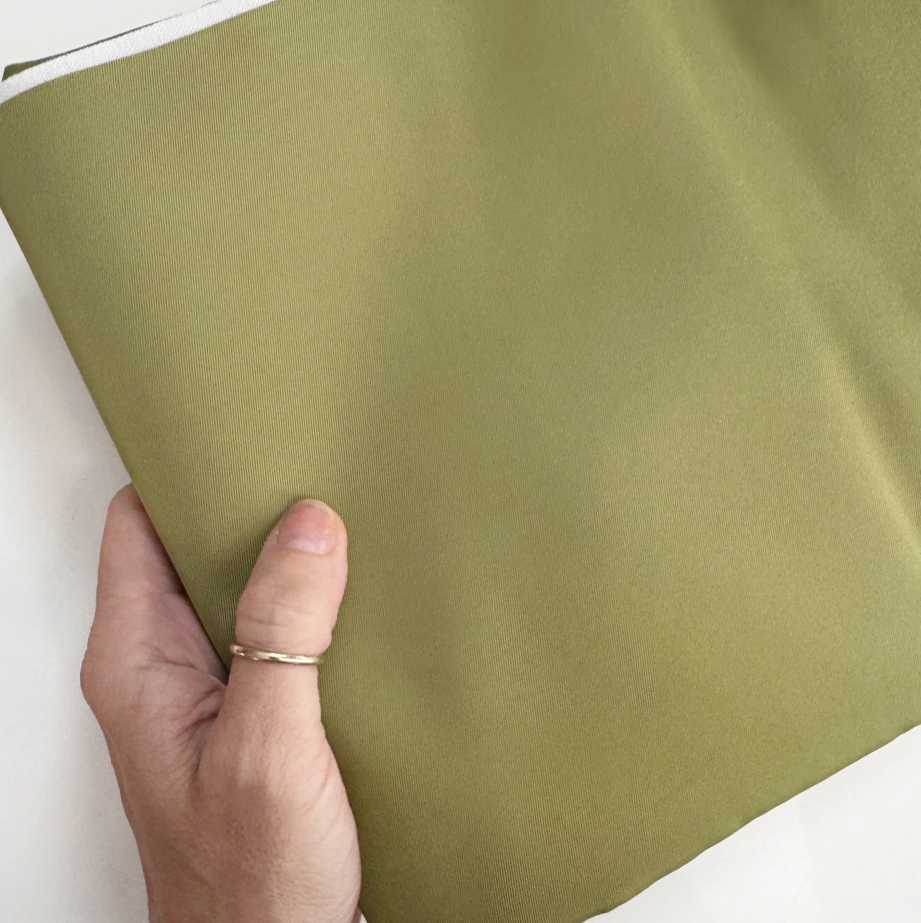 Light olive twill bonded nylon fabric with durable water-resistant backing, ideal for bag linings, backpacks, totes, and sewing projects.