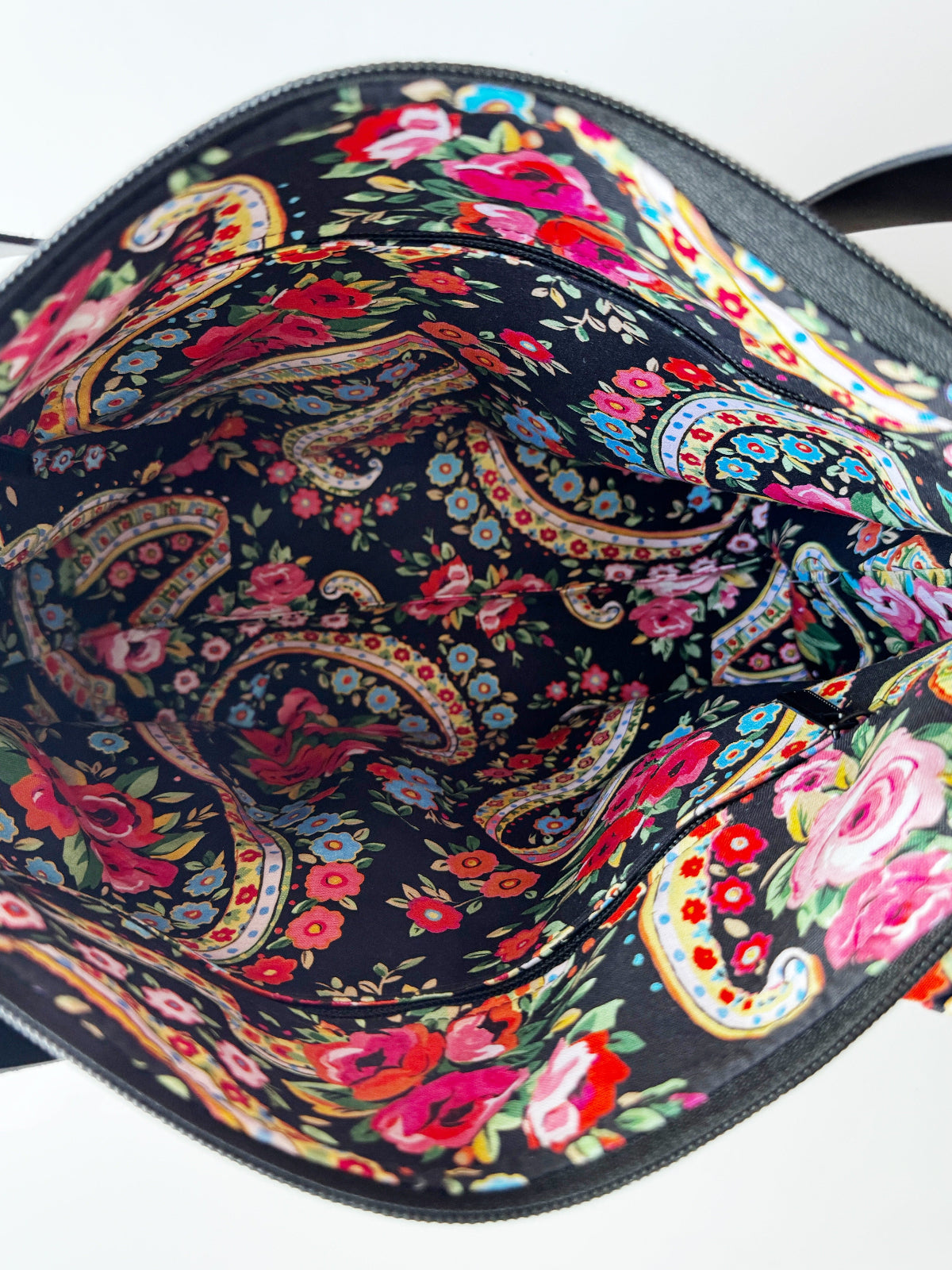 Colorful floral and paisley patterned bag on a white background