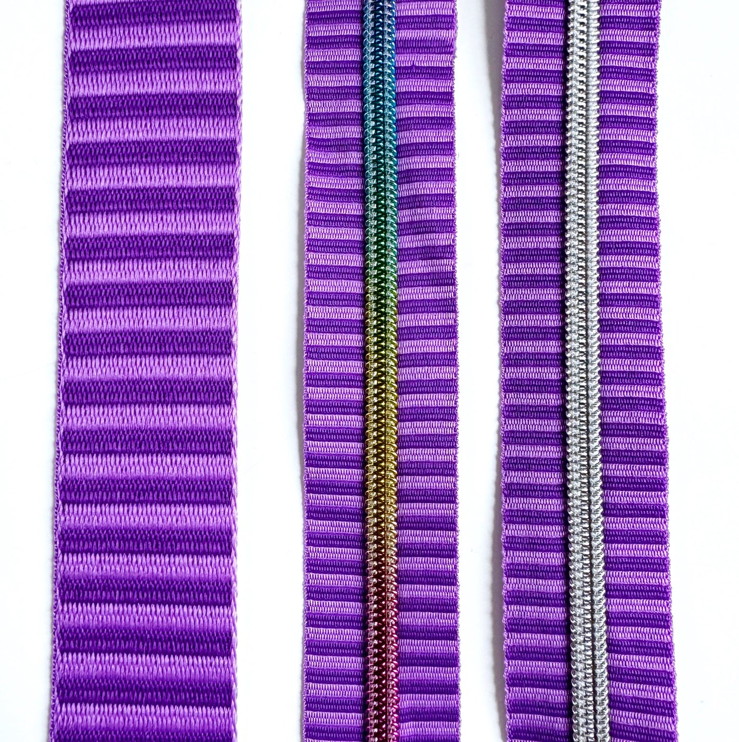 A matching purple bag making set featuring a thick, two-tone purple striped jacquard woven webbing strap on the left, a continuous zipper tape with rainbow metallic coil teeth in the center, and a matching purple zipper tape with metallic silver coil teeth on the right.
