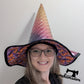 Person wearing a colorful witch hat with a white background, featuring the brand 'margahamsews'.