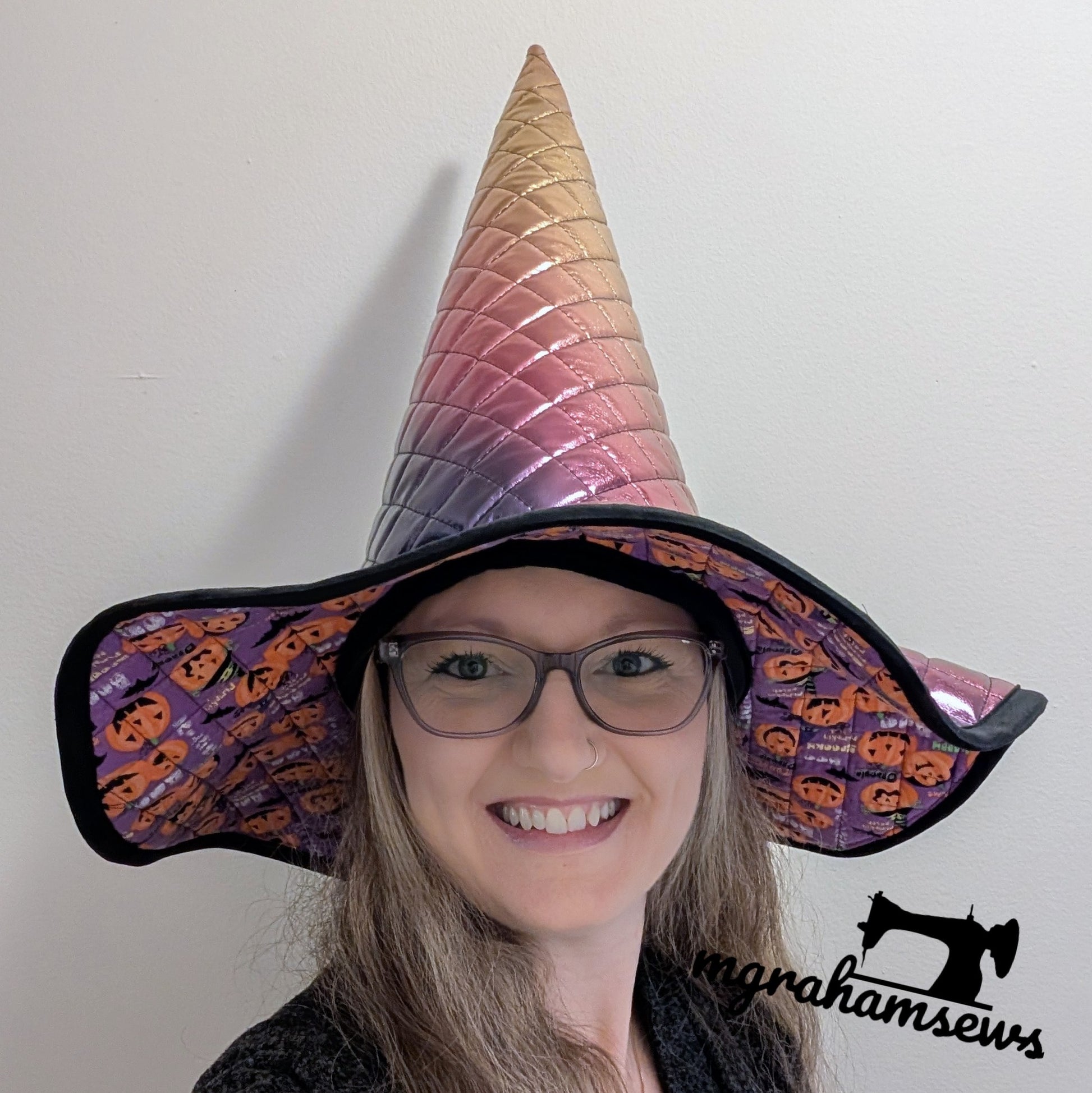 Person wearing a colorful witch hat with a white background, featuring the brand 'margahamsews'.