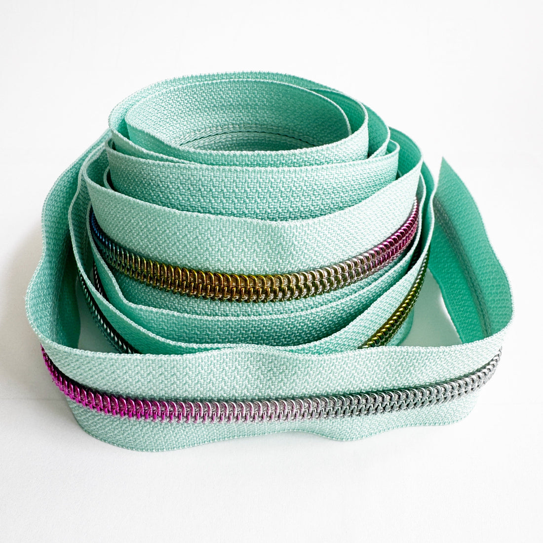 Mint green zippers with various colors and designs on a white background