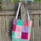 Handmade patchwork project bag with a durable Moonglow Teal vinyl base and colorful quilted fabric squares.