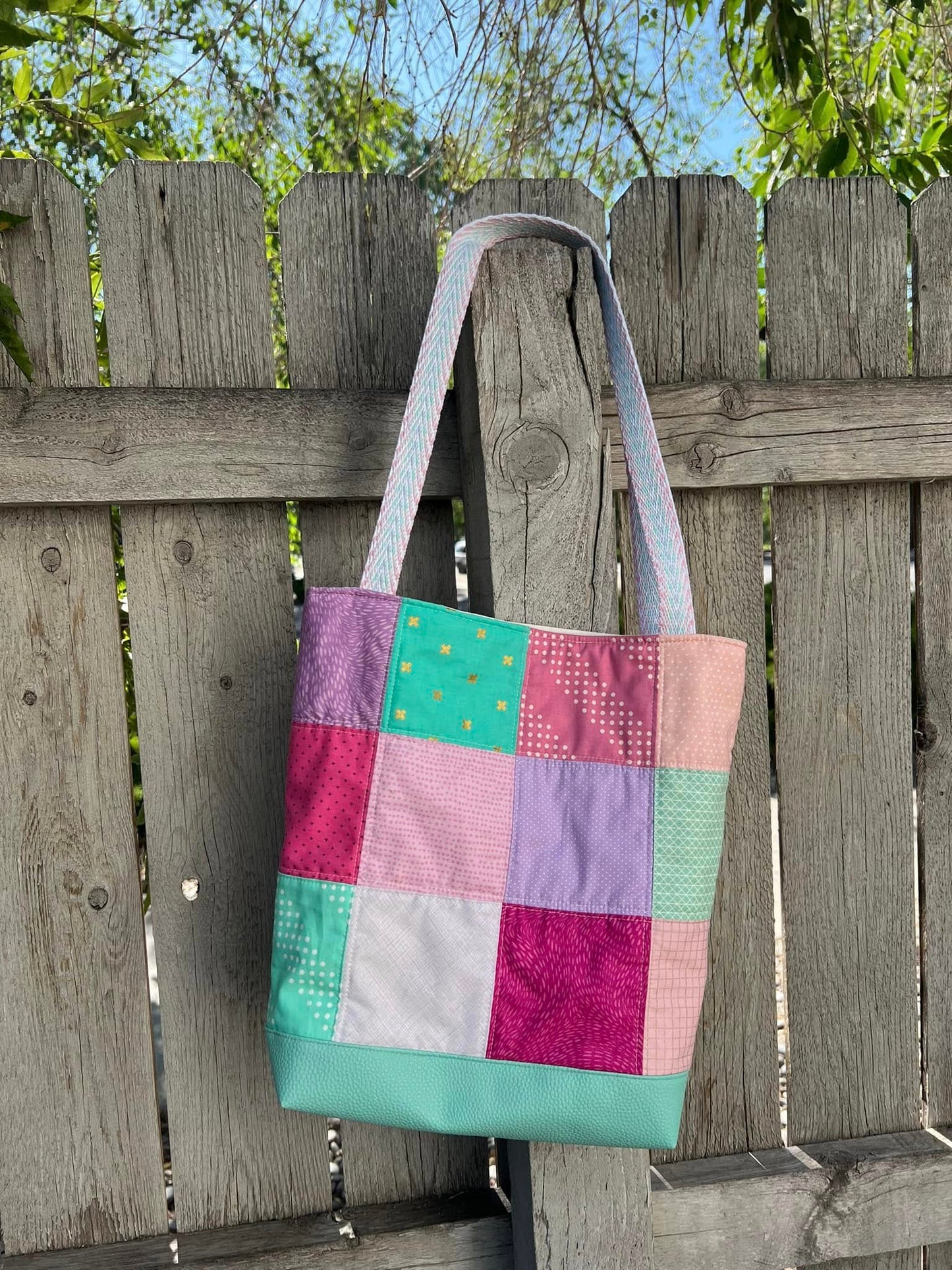 Handmade patchwork project bag with a durable Moonglow Teal vinyl base and colorful quilted fabric squares.