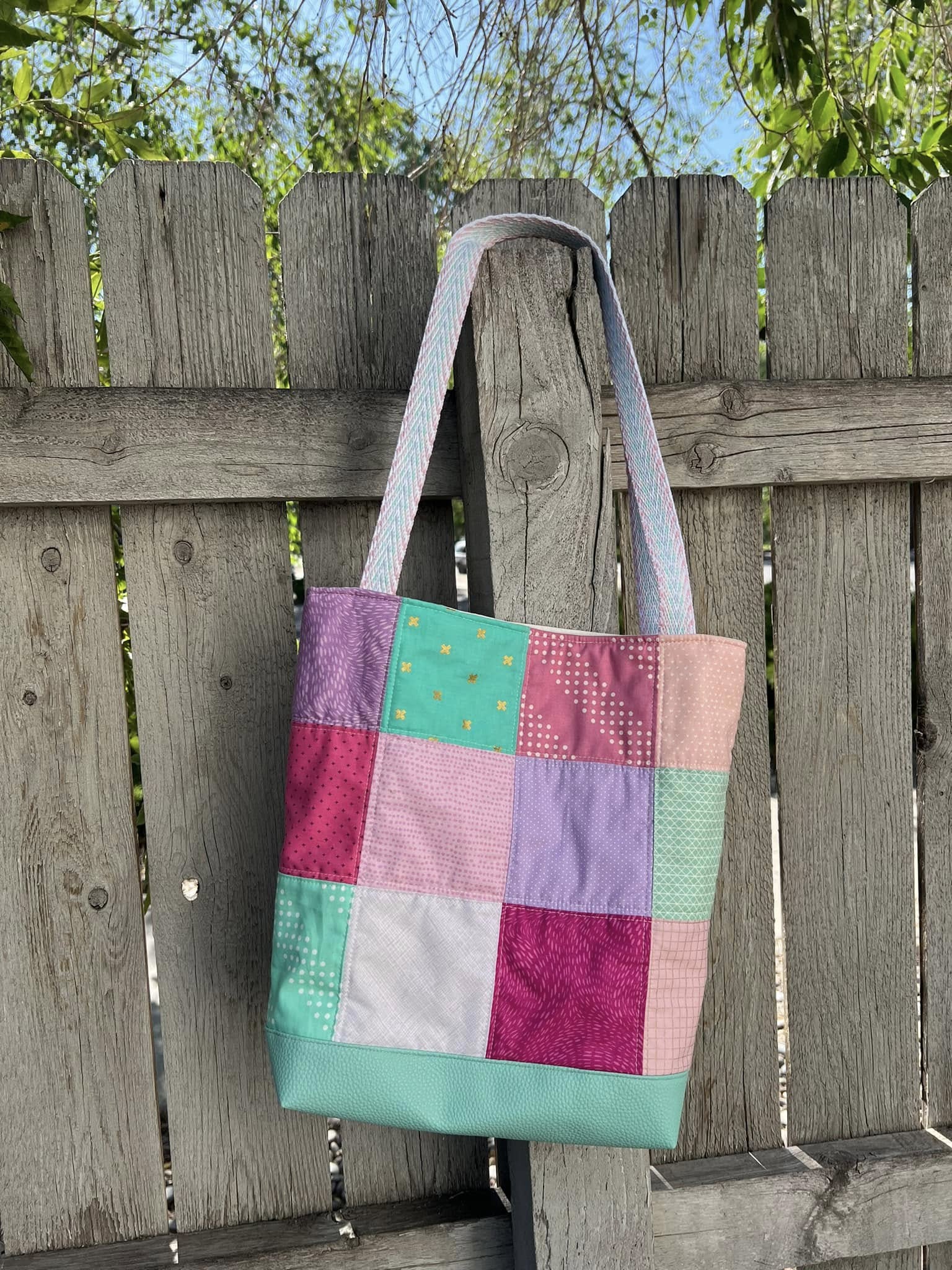 Handmade patchwork project bag with a durable Moonglow Teal vinyl base and colorful quilted fabric squares.