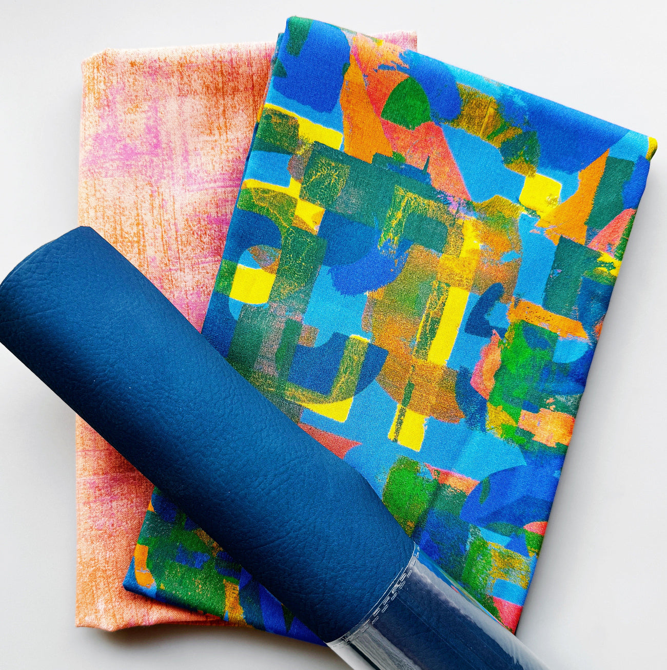 Navy blue faux leather paired with colorful abstract cotton fabric and coordinating blush pink textured cotton fabric, perfect for handbags, totes, wallets, pouches, and sewing projects.