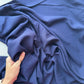 A close-up of draped navy blue fabric with a hand holding the material to show its drape and texture.