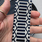 A close-up of a hand holding a woven fabric strap with a navy blue and off-white geometric pattern.