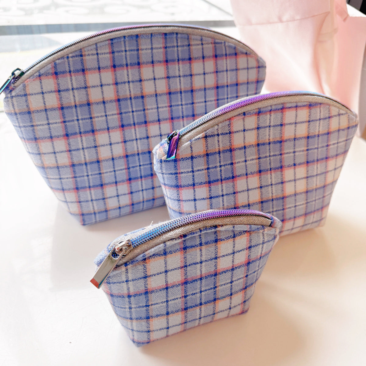 Set of blue plaid shell-shaped zipper pouches featuring a soft tartan pattern in three different sizes.