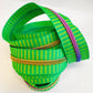 Number 5 continuous nylon coil zipper tape featuring a vibrant green and lime yellow striped jacquard woven pattern with rainbow iridescent metallic teeth, coiled against a white background.