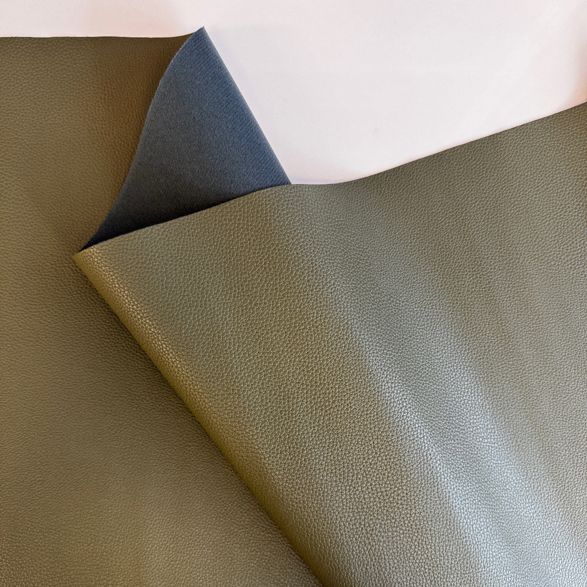 Olive green pebbled faux leather or vinyl fabric, similar to materials like the Moonglow New Olive Faux Leather used for bag making.