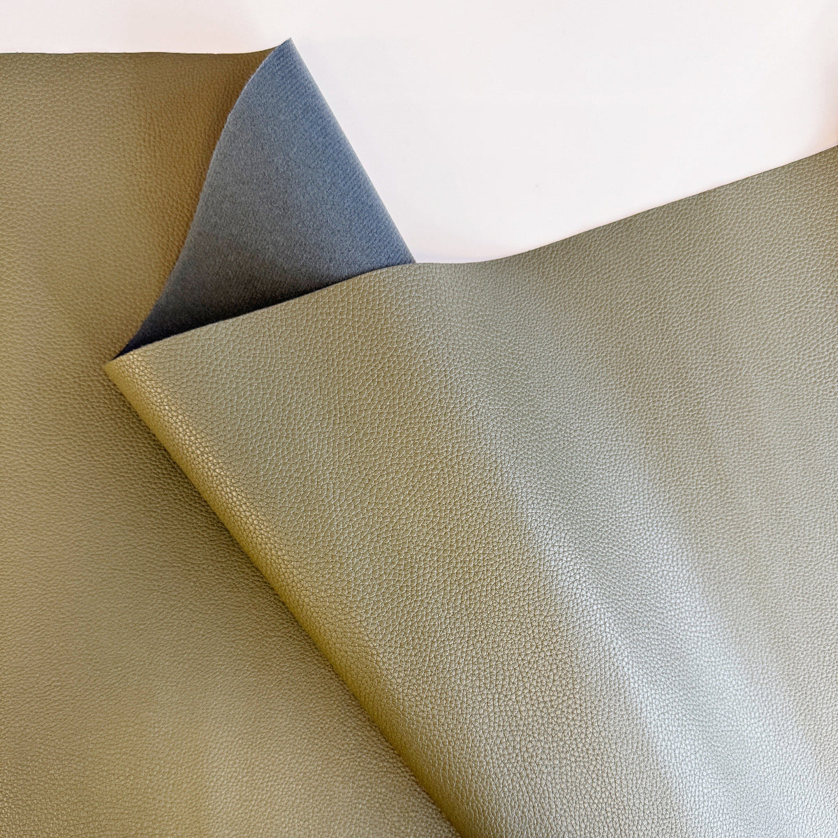 Olive green pebble-textured faux leather fabric sheet with a gray fleece backing.