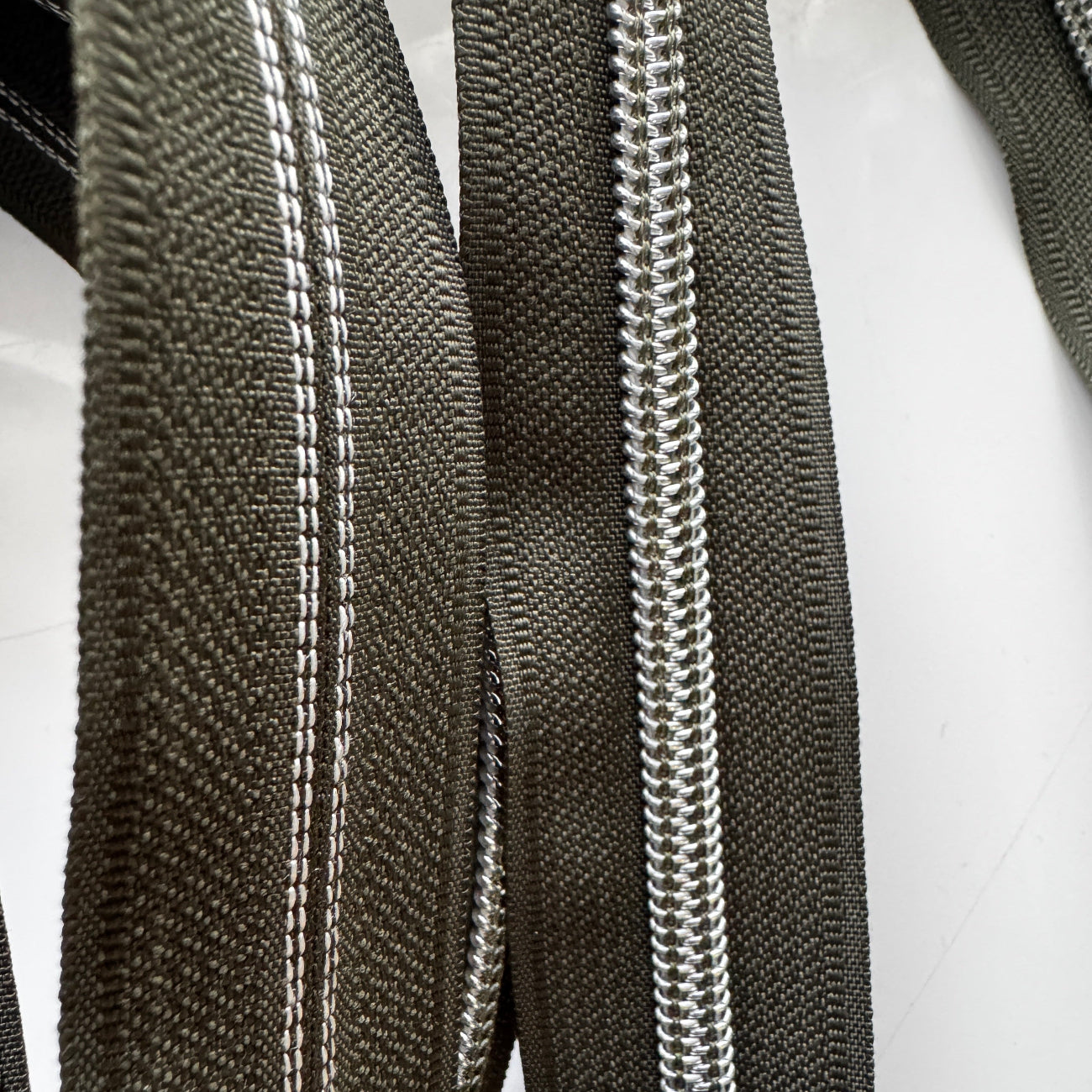 Close-up of black zippers with silver teeth on a white background