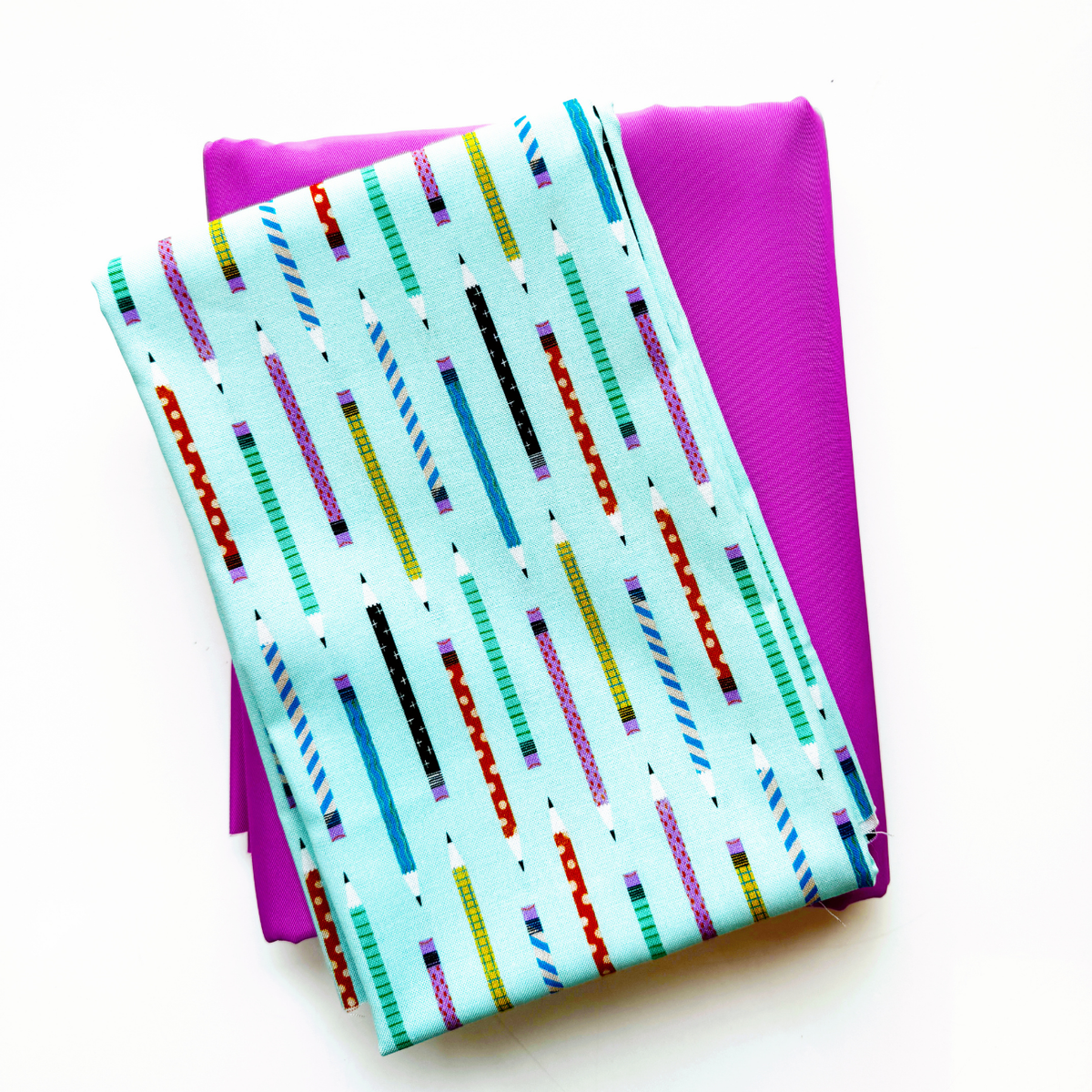 Folded Aqua Blue Pencil Thief print fabric from the Hall Pass collection by Faye Guanipa for Dear Stella Fabrics, on top of folded pink bonded nylon for bag making