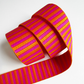 A 1.5-inch wide jacquard woven webbing strap showcasing a vibrant hot pink and orange horizontal stripe pattern, loosely coiled against a white background.