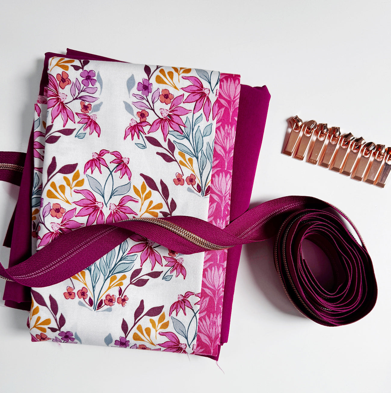 Pink floral cotton fabric bundle with coordinating solid fabric, rose gold zipper, and zipper pulls for sewing handbags, pouches, and handmade accessories.