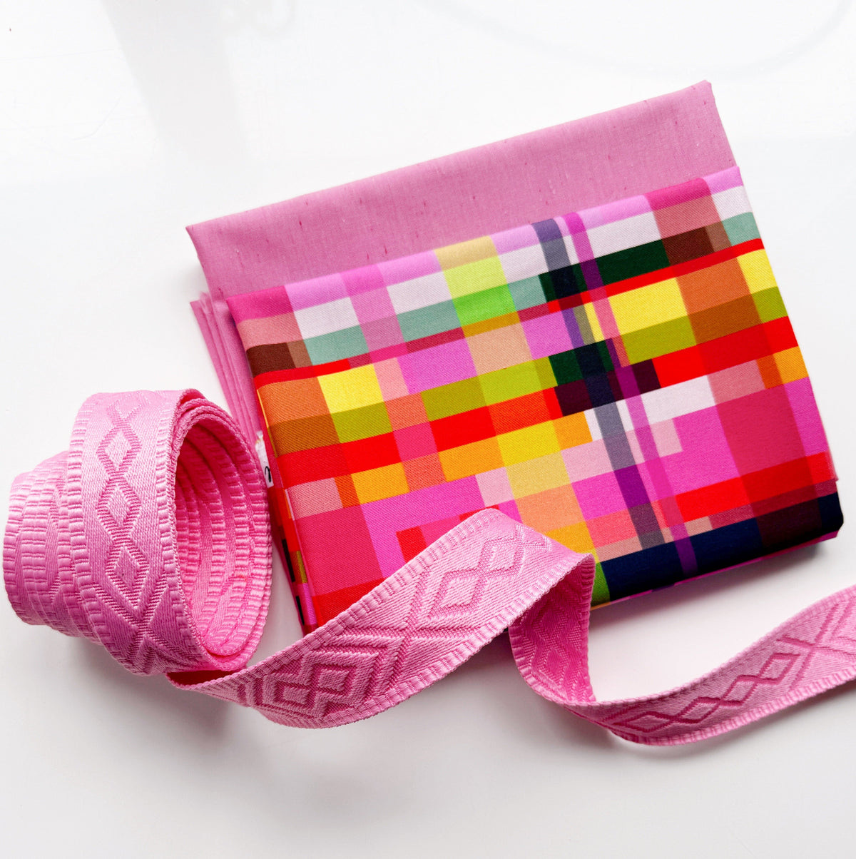 Pink multicolor plaid fabric paired with pink geometric jacquard webbing for bag making and sewing projects