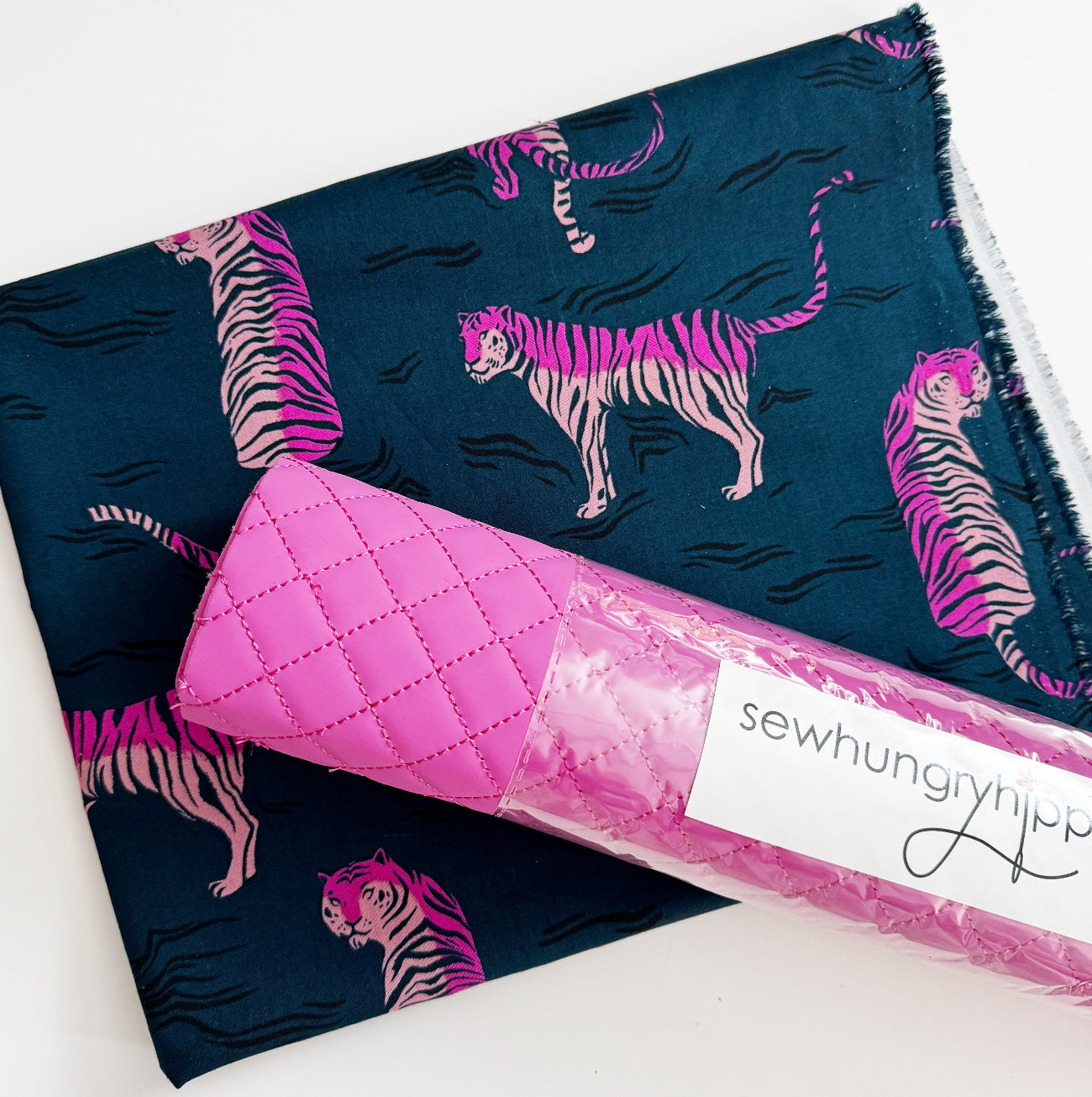 Pink quilted vinyl paired with navy cotton fabric featuring neon pink tiger print for sewing bags, wallets, and handmade accessories.