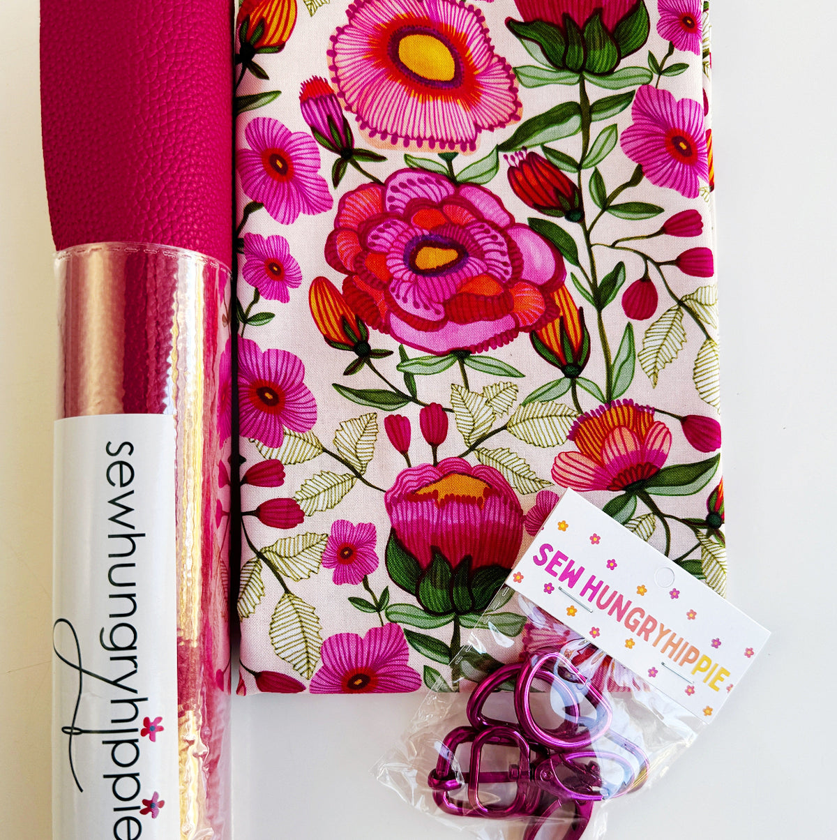 Pink vinyl, floral fabric, and pink bag hardware for sewing and bag-making projects